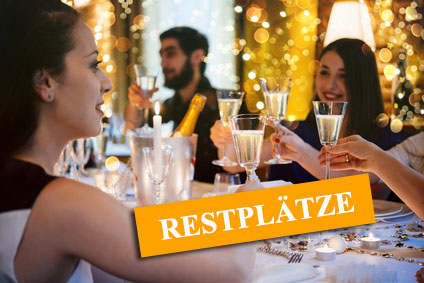 Eine elegante Gruppe von Menschen hebt ihre Gläser bei einem festlichen Abendessen an, um auf den besonderen Anlass anzustoßen und der Hinweis auf "Restplätze"