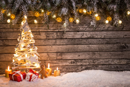 Hier sehen wir einen schön geschmückten Weihnachtsbaum mit Lichtern vor einem Holzhintergrund.