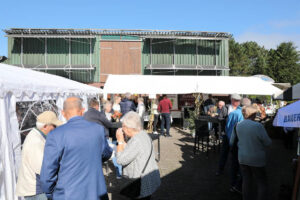 Menschen versammeln sich um Zelte bei einer eleganten Freiluftveranstaltung, umgeben von festlicher Atmosphäre.