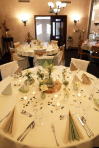 Elegant gedeckter Tisch für eine Hochzeitsfeier, geschmückt mit Blumen und feinem Geschirr, strahlt festliche Atmosphäre aus.