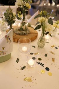 Ein eleganter Tisch mit weißer Tischdecke, geschmückt mit grünem und goldenem Konfetti für festliche Anlässe.