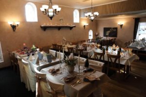 Eleganter Festsaal mit festlich gedeckten Tischen und Stühlen, bereit für ein stilvolles Abendessen.