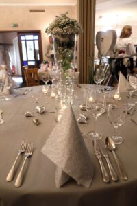 Ein eleganter Tisch, gedeckt mit feinem Besteck und kunstvoll gefalteten Servietten, strahlt Luxus und Stil aus.