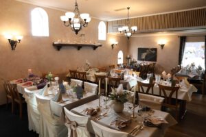 Elegant dekorierte Alte Scheune mit festlich gedeckten Tischen und Stühlen, bereit für eine traumhafte Hochzeitsfeier.