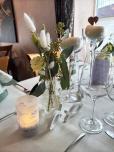 Ein eleganter Tisch mit einer Kerze, Weingläsern und einer Blumenvase, die eine romantische Atmosphäre schafft.