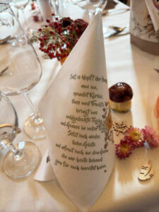 Ein elegantes Tischtuch mit einer kunstvoll gefalteten Serviette, die stilvoll auf einem gedeckten Tisch liegt.