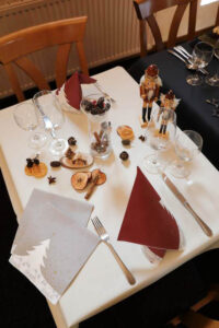 Ein eleganter Tisch geschmückt mit einem festlichen Weihnachtsbaum auf den Servietten und zauberhaften Weihnachtsdekorationen.