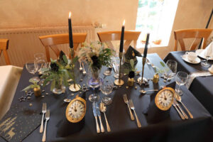 Ein eleganter Tisch mit schwarzer Tischdecke und glänzendem Besteck, der eine luxuriöse Atmosphäre ausstrahlt.