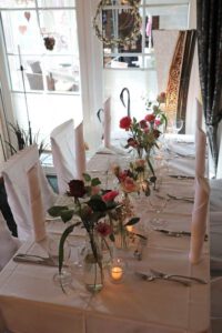 Ein eleganter Tisch mit weißer Tischdecke, geschmückt mit zarten Blumenarrangements, strahlt Anmut und Stil aus.