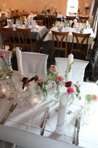 Ein festlich gedeckter Tisch für eine Hochzeitsfeier, geschmückt mit Blumen und Kerzen.